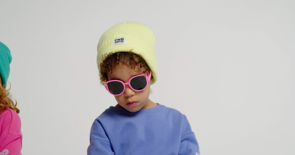 young child wearing a gym + coffee hat on a video set